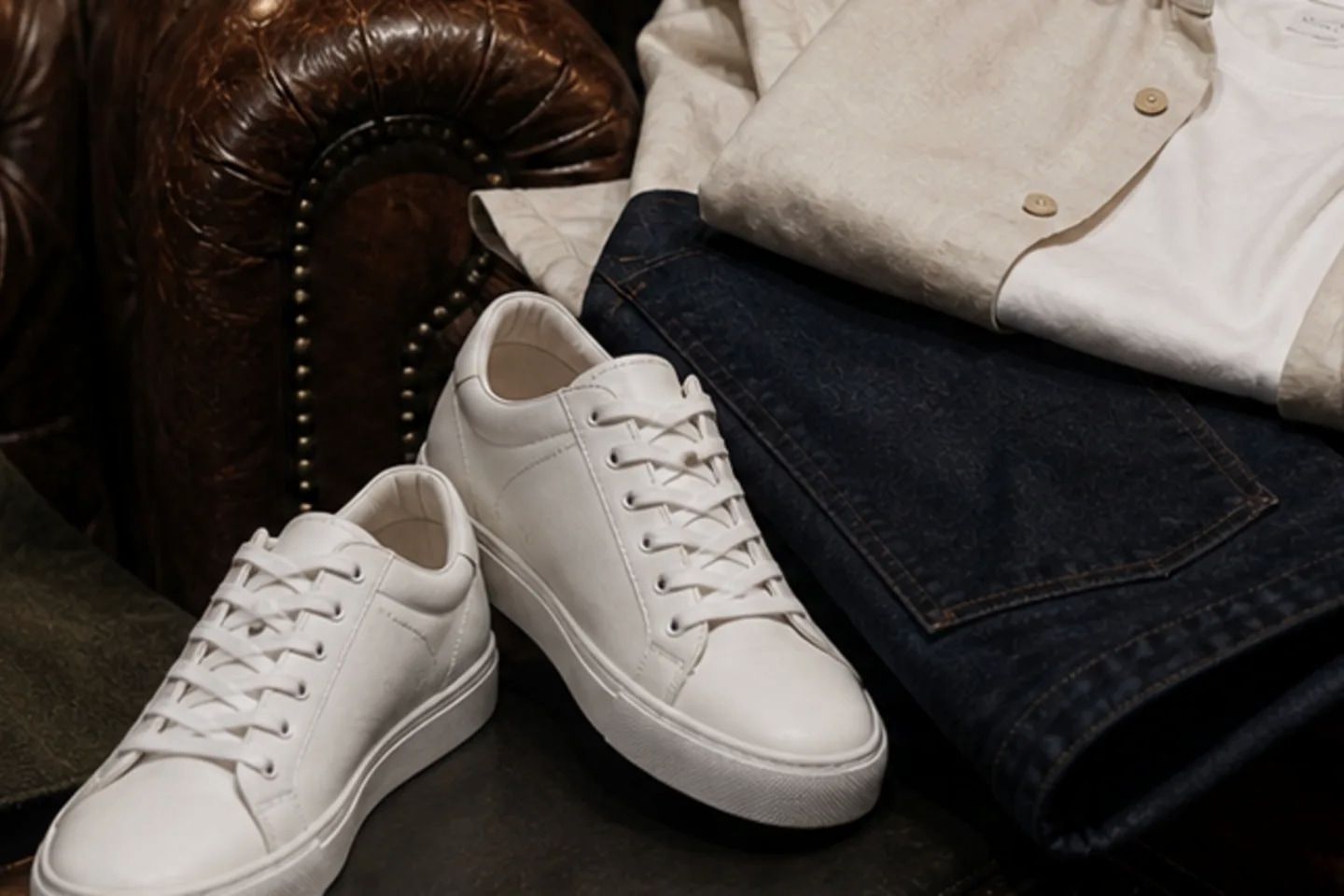 Clean white leather sneakers beside a shoe brush.