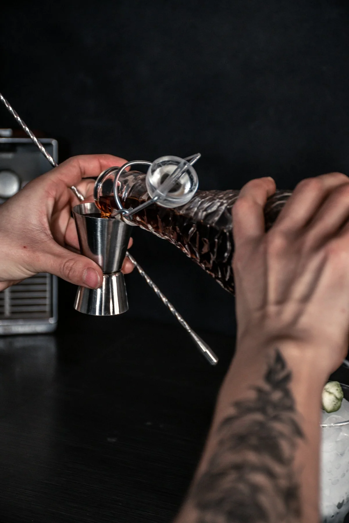 Jigger and bar tools in use while measuring a drink.
